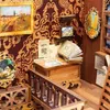 A miniature book nook scene with intricate details, including a wooden chest, books, a framed painting, and decorative wallpaper. Voir les images du produit