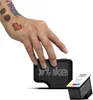 A hand with temporary tattoos is shown holding a black Prinker device, with an ink cartridge next to it. Anteprima dell’immagine prodotto