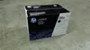 A black and white HP LaserJet toner cartridge box sits on a concrete floor. Náhľad obrázku produktu
