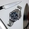 A G-SHOCK watch is placed on a light gray surface next to two knives. Náhled obrázku produktu