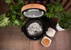A rice cooker filled with rice and herbs, surrounded by houseplants. Voir les images du produit