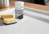 A cleaning product and sponge are placed on a white sink surface. Produktbild-Vorschau