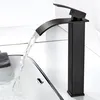 A black waterfall faucet in a modern bathroom, with water flowing into a sink. Produktbild-Vorschau