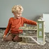 A young boy is playing with a wooden toy garage on a fluffy rug. Produktbild-Vorschau