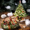 Christmas-themed decorations on a wooden surface with a Christmas tree in the background. Náhľad obrázku produktu
