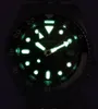 A close-up of a watch face with luminous hands and markers glowing in the dark. Produktbild-Vorschau
