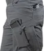 A close-up view of gray tactical pants with multiple pockets. One pocket holds a rifle magazine, and another, zipped pocket is partially open. Náhled obrázku produktu