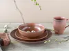 A rustic table setting with brown ceramic dishes, quail eggs, and a sprig of greenery. Náhľad obrázku produktu