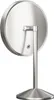A close-up, rear view of a silver, round makeup mirror with a stand, set against a white background. Produktbild-Vorschau