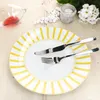 A plate with cutlery on a wooden table, with a wine glass and flowers in the background. Produktbild-Vorschau