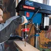 A person is using a drill press in a workshop setting. Produktbild-Vorschau