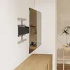 A TV wall mount is attached to a white wall, holding a large flat-screen TV. A wooden cabinet is visible below the TV, and a small table with a plant is in the background. Podgląd zdjęcia produktu