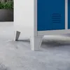 Close-up of the bottom of a white and blue metal locker on a concrete floor. Anteprima dell’immagine prodotto