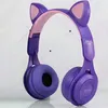 A pair of purple headphones with pink accents and cat ears is displayed against a light gray and white tiled background. Náhľad obrázku produktu