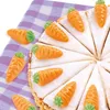 A close-up view of a cake decorated with marzipan carrots, placed on a purple and white checkered cloth. Produktbild-Vorschau