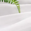 A close-up shot of white fabric with a green leaf resting on it. Produktbild-Vorschau