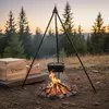 A Dutch oven set is being used over a campfire in a forest setting at dusk. Produktbild-Vorschau