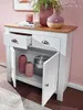 A white sideboard with a wooden top, featuring two drawers and two doors, is shown in a room with a pink wall and wooden floor. Decorative items like vases, a candle, and a plant are placed on top and inside the sideboard. Voir les images du produit