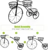 The image shows a black metal bicycle-shaped plant stand with three baskets. Below the product image, there are diagrams illustrating the assembly process with numbered steps and plus/equals signs. Produktbild-Vorschau