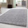 A shaggy rug is placed on a light-colored floor in a room with a chair and a plant. Produktbild-Vorschau