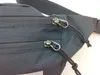 A close-up view of the zippers and fabric of a black hip bag. Anteprima dell’immagine prodotto