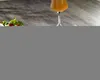 A glass of orange liquid sits on a wooden surface next to some greens and red berries. Produktbild-Vorschau
