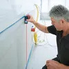 A man is using a laser distance measurer to measure a wall during construction or renovation. Voir les images du produit
