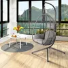 A hanging chair with a small table and flowers in a room with large windows overlooking a forest. Produktbild-Vorschau