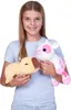 A young girl is holding two plush toys, a cow and a capybara, in front of a white background. Produktbild-Vorschau