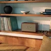 A Marshall speaker sits on a shelf next to records and decorative items. Produktbild-Vorschau