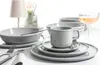 A table setting with a 30-piece dinnerware set, including bowls, plates, and a mug, along with a glass of rosé wine. Produktbild-Vorschau