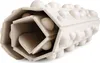 A close-up, studio shot of a textured, cylindrical object with a hexagonal cross-section, made of a light-colored, possibly recycled material. The object has raised, rounded bumps on its exterior and appears to be hollow with internal hexagonal structures. Náhľad obrázku produktu