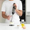 A person is using an immersion blender to make mayonnaise in a glass. Podgląd zdjęcia produktu