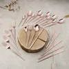 A set of rose gold cutlery arranged on a wooden surface and a textured background. Anteprima dell’immagine prodotto