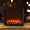 A black electric fireplace with LED flames sits on a wooden surface, with a blurred background of bokeh lights. Náhled obrázku produktu