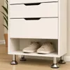 A close-up of a white storage unit with two shelves holding a pair of beige sneakers. The unit has sleek, modern chrome legs. The background is a neutral wall and floor. Produktbild-Vorschau