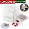 A collection of empty tea bags, some filled with dried flowers and tea leaves, and a cup of tea. Produktbild-Vorschau