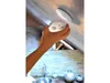 A hand is installing a white smoke detector onto a ceiling. Produktbild-Vorschau