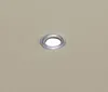 A close-up of a beige fabric with a metal grommet. Náhled obrázku produktu