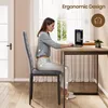 A woman is sitting at a desk, using a laptop, with a chair and a window in the background. Podgląd zdjęcia produktu