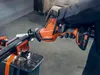A person wearing gloves is using a cordless reciprocating saw to cut a metal bar clamped in a vise. Produktbild-Vorschau