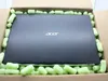 A closed laptop is inside a cardboard box, cushioned by light green packing peanuts. Produktbild-Vorschau