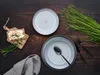 A table setting with plates, cutlery, and a small snack, accompanied by greenery. Náhľad obrázku produktu