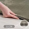 A hand is shown lifting the edge of a green rug to demonstrate its thickness. Produktbild-Vorschau