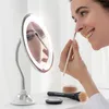 A woman is applying makeup using a lighted magnifying mirror. Podgląd zdjęcia produktu