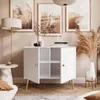 A modern living room scene featuring a white two-door cabinet with wooden legs, styled with decorative items and artwork. Produktbild-Vorschau