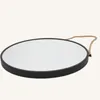 A round mirror with a black frame and a rope hanger, set against a plain white background. Produktbild-Vorschau