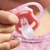 A close-up shot of a person's hand holding a pink baby pacifier. Anteprima dell’immagine prodotto