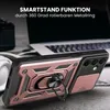 A close-up of a rose gold and black smartphone case with a built-in ring stand, placed on a textured surface with a blurred laptop and headphones in the background. Produktbild-Vorschau