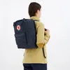 A person wearing a yellow jacket and blue pants is seen from behind, wearing a blue backpack. Produktbild-Vorschau